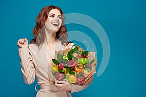 beautiful woman beige coat fruit bouquet in hands blue background