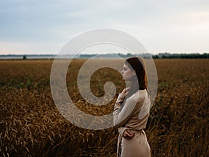 beautiful woman in beige sundress in nature near dry fields