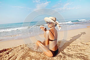 Beautiful Woman in Bikini Applying Sun Cream on Tanned Shoulder. Sun Protection. Skin and Body Care.