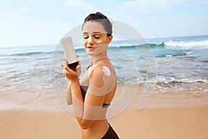 Beautiful woman in bikini applying sun cream on tanned  shoulder. Sun protection. Skin and body care.