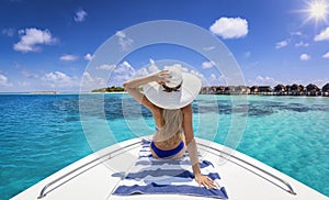 A beautiful woman in bikini with hat sits on a yacht and enjoys the summer holiday photo