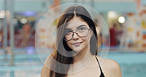 Beautiful woman in bikini posing near the swimming pool. Portrait of fashion model girl in swimsuit and glasses