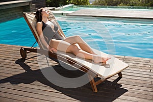 Beautiful woman in bikini relaxing by swimming pool