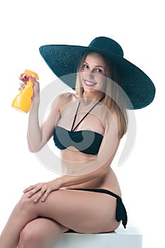 Beautiful woman in bikini sits with spray bottle