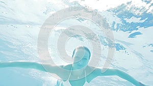 Beautiful woman in bikini swiming underwater in swimming pool.