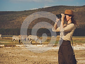 Beautiful woman with binoculars at savanna in Kenya