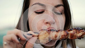 Beautiful woman biting huge pieces of meat eating with hands angry inappropriate in close up view