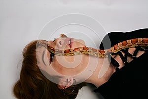 Beautiful woman in black bodywear and snake. Ginger model girl with fashion perfect make up