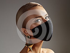 Beautiful Woman with Black Face Mask. Fashion Eye Make-up and Gold Accessories. Protection hygiene in virus pandemic