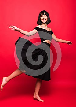 Beautiful woman in black flying dress isolated on red background