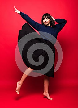 Beautiful woman in black flying dress isolated on red background