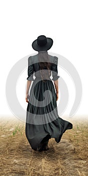 Beautiful woman in black hat and green dress walking in wheat field. Amish woman walking away.