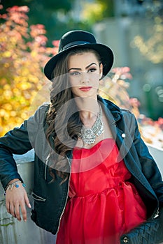 Beautiful woman with black hat posing in autumnal park. Young brunette spending time during autumn in forest