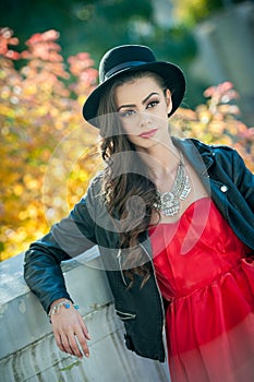 Beautiful woman with black hat posing in autumnal park. Young brunette spending time during autumn in forest