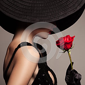 Beautiful woman in black hat and red rose