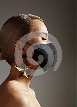 Beautiful Woman with Black Medical Mask on Face. Festive Look with Gold Accessory. Protection Covid-19 Pandemic