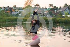 A beautiful woman in a black medical mask stands in the river.rest in the pandemic