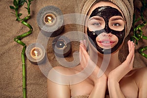 Beautiful woman with black purifying black charcoal mask on her face. Beauty model girl with black facial peel-off mask photo