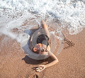 Beautiful woman in a bathing suit lying on the sand by the sea top view