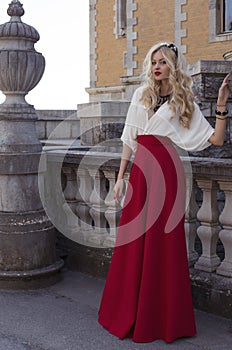 Beautiful woman with blond hair in elegant dress at park