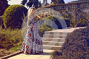 Beautiful woman with blond hair in elegant dress at park