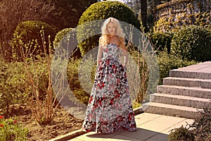 Beautiful woman with blond hair in elegant dress at park