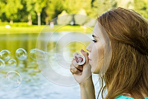 Beautiful woman blowing bubbles in the summe near the lake