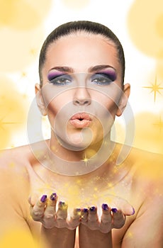 Beautiful woman blowing shimmer and golden stars