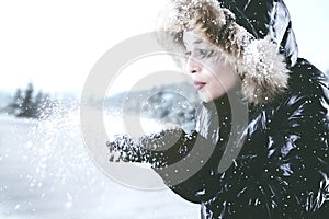 Beautiful woman blowing snow from hands