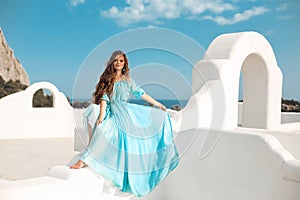 Beautiful woman in blue dress on the roof of Santorini island, Greece. Fashion outdoor photo of beautiful girl model on summer