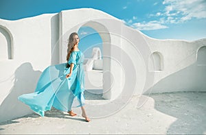 Beautiful woman in blue dress on the roof of Santorini island, Greece. Fashion outdoor photo of beautiful girl model on summer