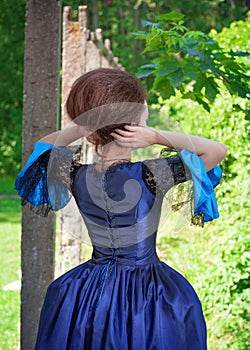 Beautiful woman in blue medieval dress outdoor, back