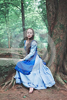 Beautiful woman in blue medieval dress sitting