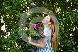 Beautiful woman in a blue summer dress with lilac flowers in a blooming garden. Spring Blossom