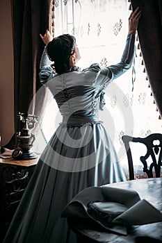 Beautiful woman in blue vintage 1800s early 1900s clothing Cottagecore Edwardian Victorian Epoque dress in old interior