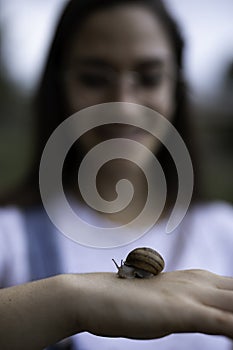 Beautiful woman blurred holding a snail in her hands outdoors