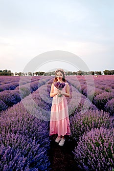 Beautiful woman with a bouquet of lavender in a lavender field