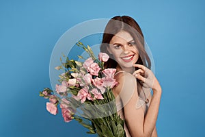 Beautiful woman with a bouquet of pink flowers on a blue background spring model