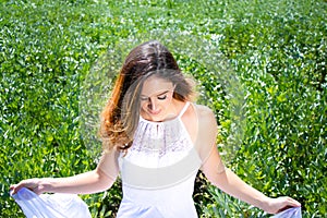 Beautiful woman, bride with blue eyes and brown hair walks through crop field on a sunny summer`s day