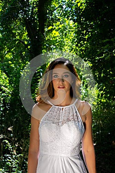 Beautiful woman, bride with blue eyes and brown hair walks through leafy woods, woodland on a bright sunny summer`s day