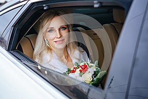 Beautiful woman bride with a bouquet of flowers and a man sitting in the car, looking out the window