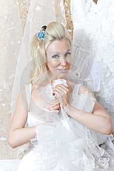 Beautiful woman, the bride, with a garter on a foot near a wedding dress