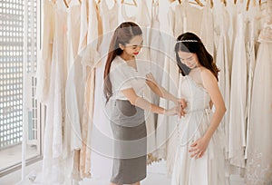 Beautiful woman bride trying on white wedding dress,Asian women tailor making adjustment on her client during fitting