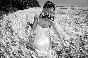 Beautiful woman, bride walked through corn field holding silver shoes on a sunny summer`s day