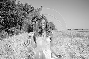 Beautiful woman, bride walked through corn field holding silver shoes on a sunny summer`s day