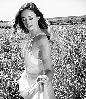 Beautiful woman, bride walks through crop field on a sunny summer`s day