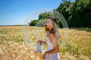 Beautiful woman, bride with blue eyes and brown hair walks through corn field on a sunny summer`s day, laughing