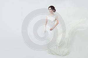 Beautiful woman bride in white lacy dress. Cute fiancee girl with blowing gown on banner background with copy space