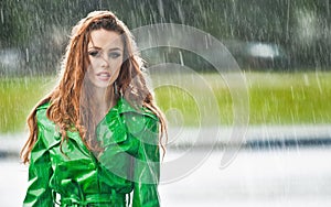 Beautiful woman in bright green coat posing in the rain