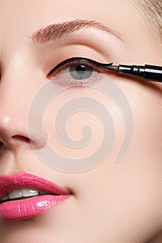 Beautiful woman with bright make up eye with black liner makeup. Fashion arrow shape. Chic evening make-up. Makeup beauty wit